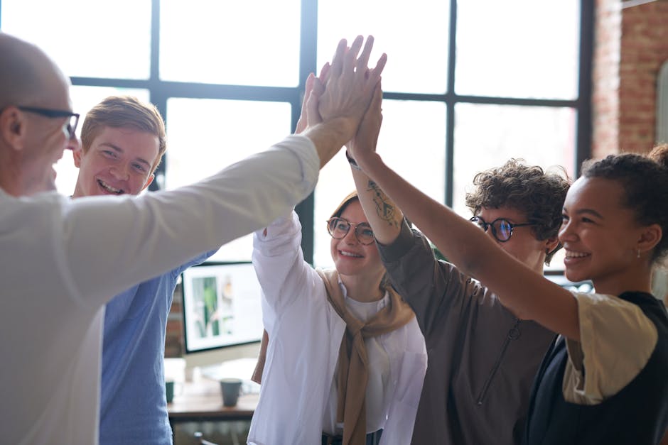 A diverse team of professionals celebrating success with a high five in a modern office.